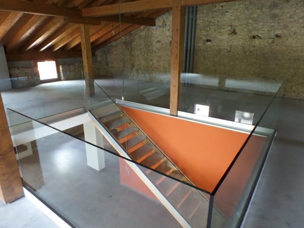 Una escalera con barandilla de cristal que conduce al segundo piso.