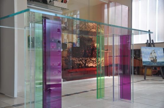 Una mesa de cristal con trozos de vidrio de color morado, verde y azul.