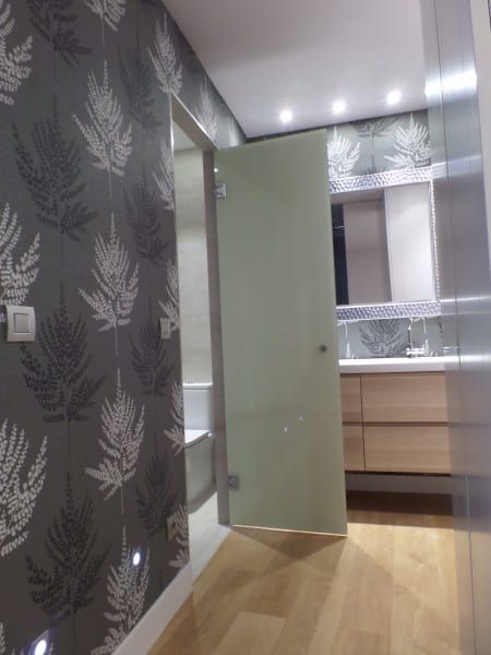 Un pasillo con una puerta de cristal que conduce a un baño.