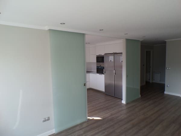 Una habitación vacía con una puerta corrediza de vidrio que conduce a una cocina.