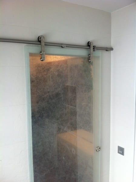 Un baño con una puerta corrediza de vidrio que parece una puerta corrediza de granero.