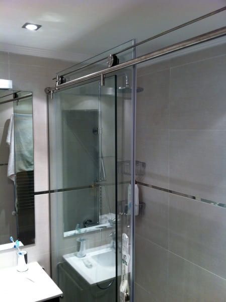 Un baño con lavabo y ducha con puerta corrediza de cristal.