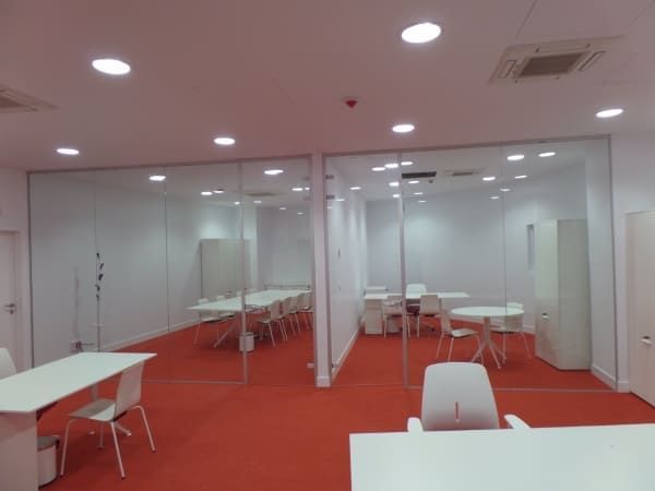 Una habitación con mesas y sillas y una alfombra roja.