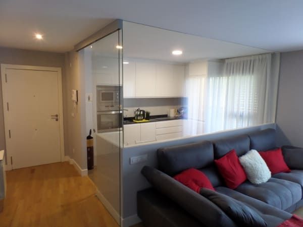 Una sala de estar con un sofá y una cocina al fondo.