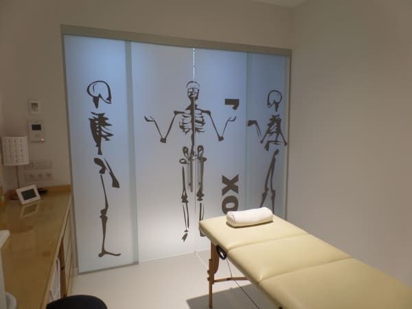 Una mesa de masajes en una habitación con esqueletos en la pared.