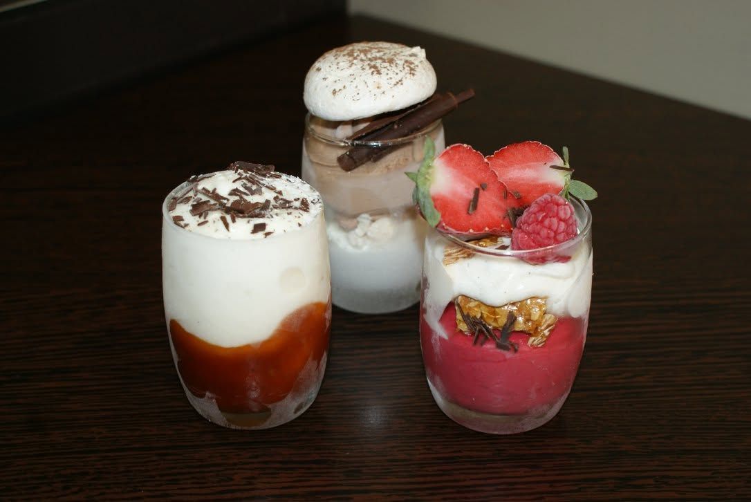 Trois glaces en verrine, composés de couches de crème, de fruits et de chocolat.