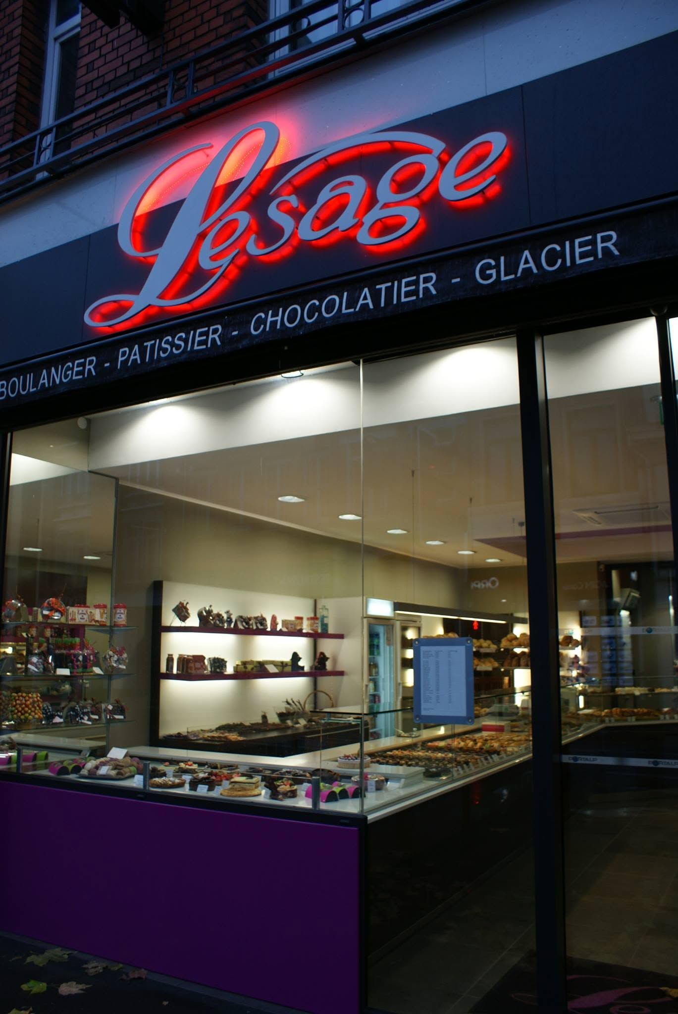 Façade de la pâtisserie avec l'enseigne illuminée.