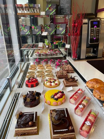 Vitrine de boulangerie présentant un assortiment de pâtisseries, gâteaux, coffrets disposés sur des étagères et des plateaux.