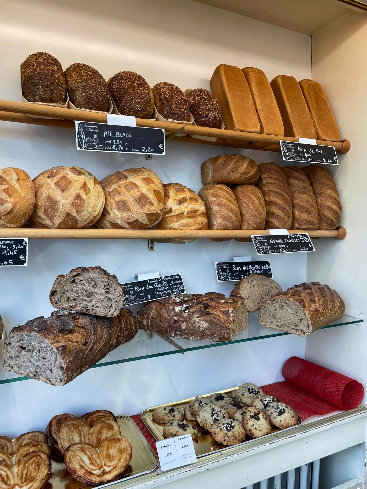 Étagères de boulangerie présentant un assortiment de pains et de petits pains.
