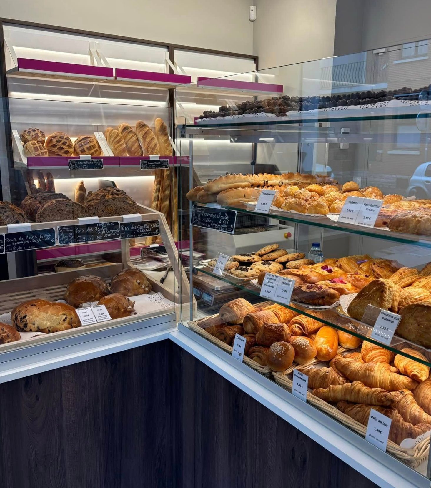 Vitrine de boulangerie remplie de pains, viennoiseries et croissants assortis derrière un verre.