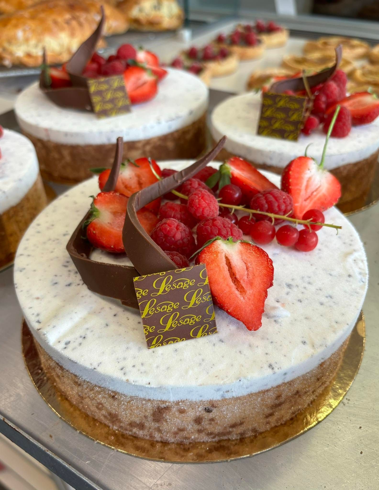 Plusieurs gâteaux couverts de crème et décorés de fraises, de framboises et de groseilles.