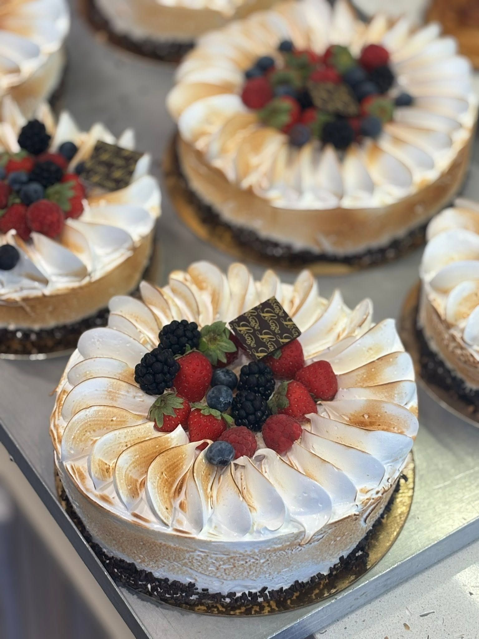 Gâteaux ronds garnis de fruits rouges et nappés de glaçage blanc, présentés sur un plateau.