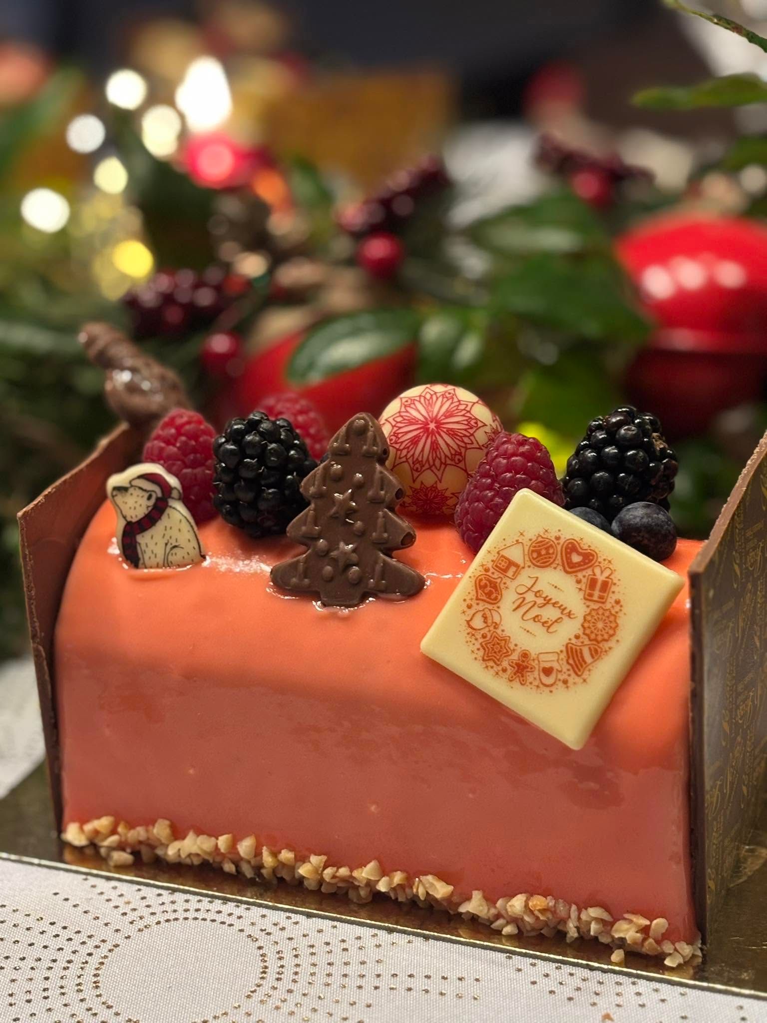 Bûche de Noël décorée de fruits rouges, de sujets en chocolat.