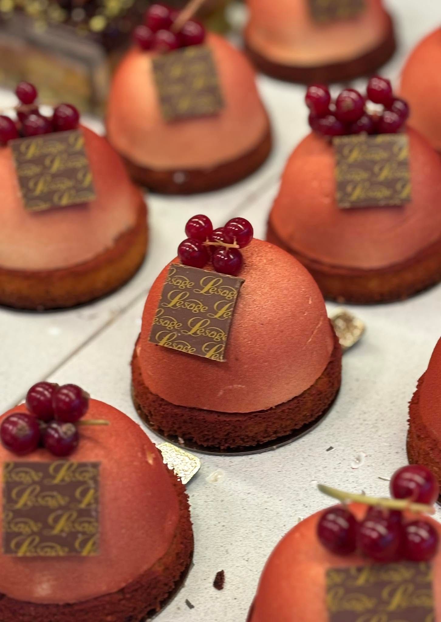 Plusieurs gâteaux individuels avec un dôme de mousse et des groseilles.
