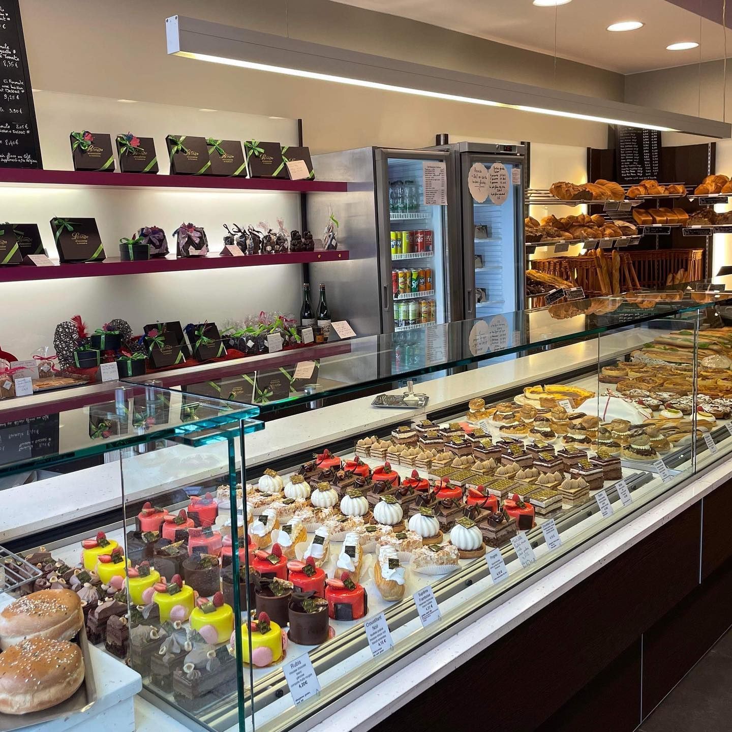 Vitrine de boulangerie présentant un assortiment de pâtisseries et de confiseries sur des étagères et des comptoirs.