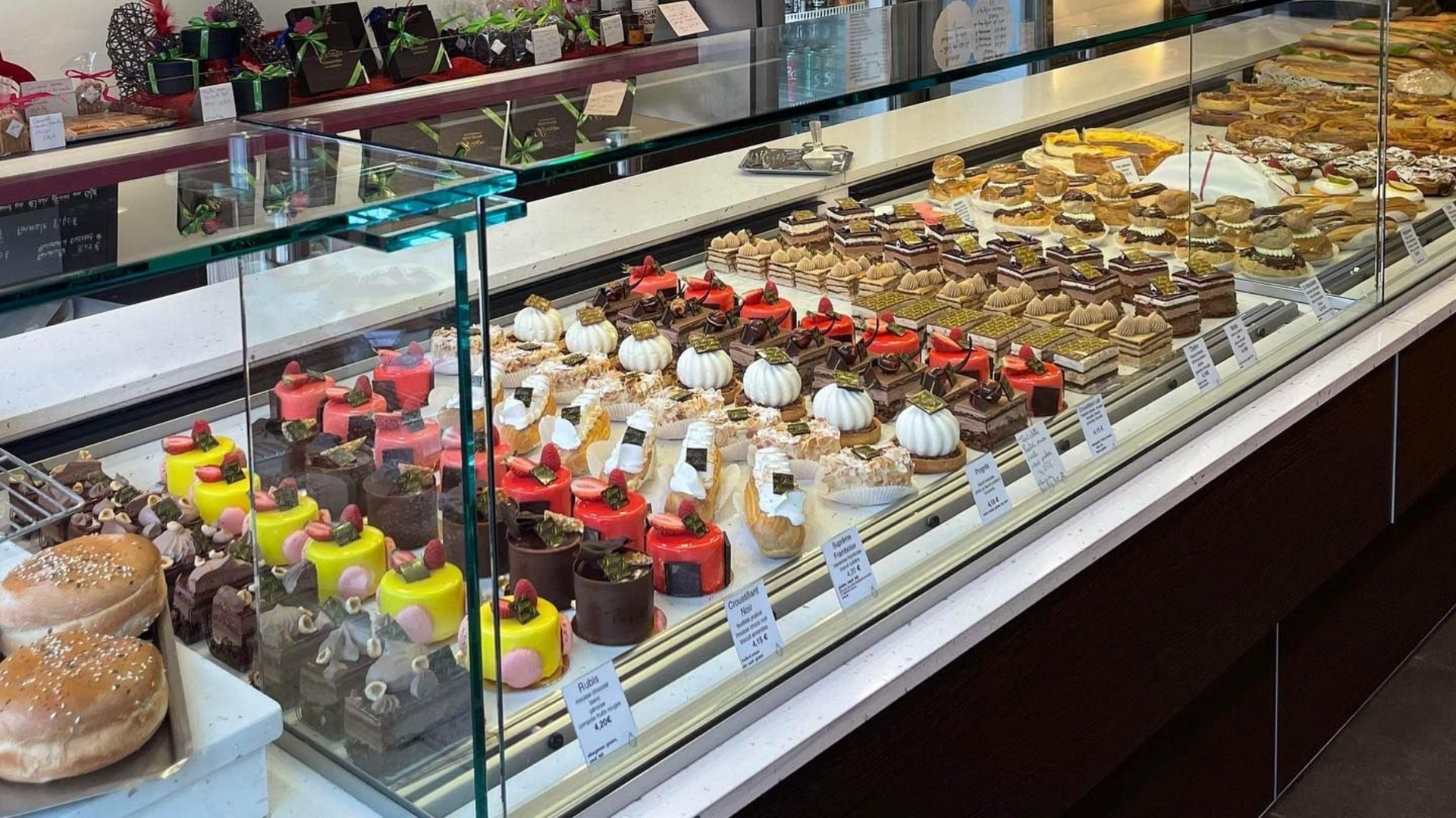 Vitrine de boulangerie remplie de pâtisseries et de desserts assortis, disposés en rangées.