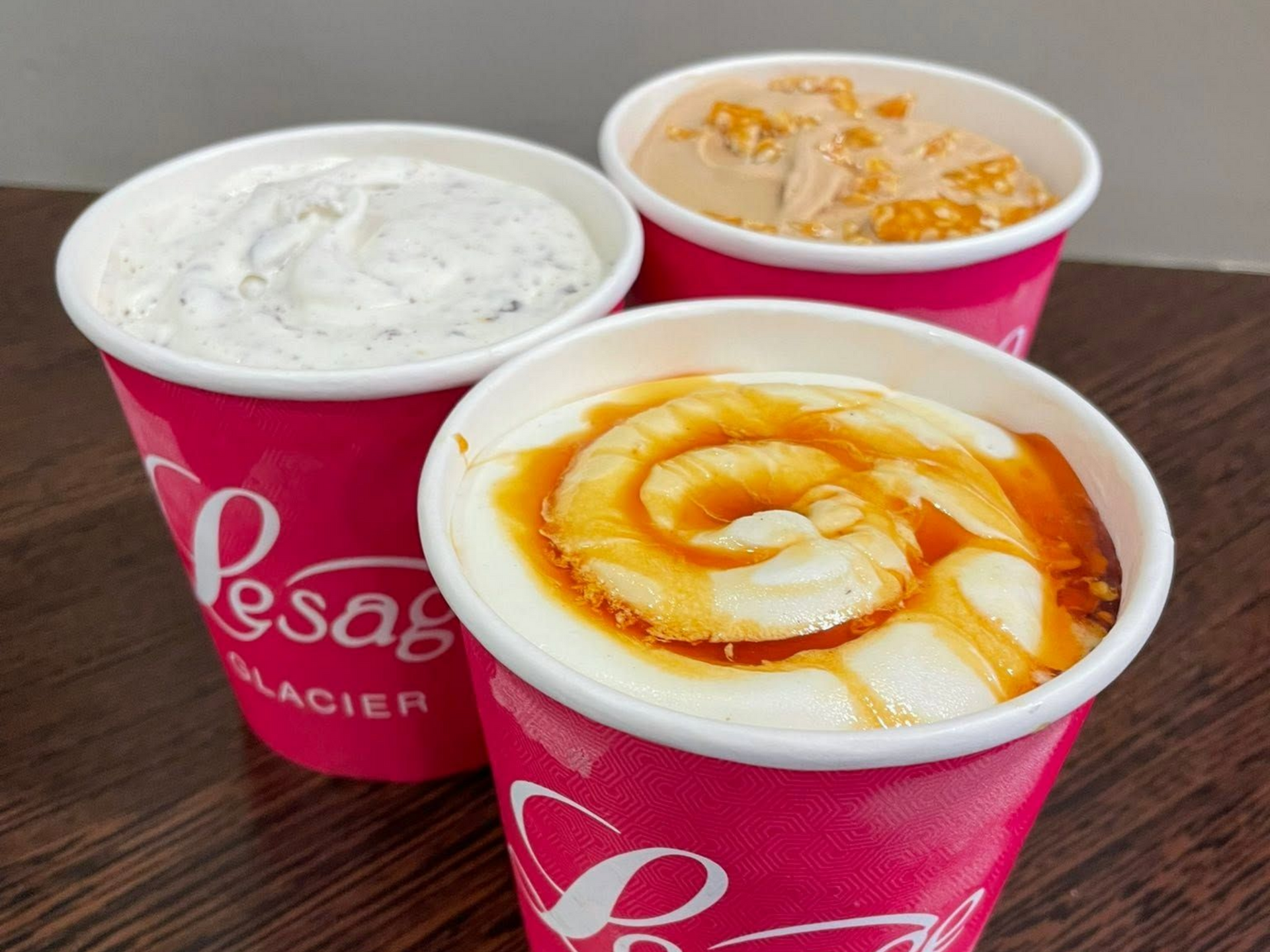 Trois cafés avec mousse et sirop, dans des gobelets en carton.