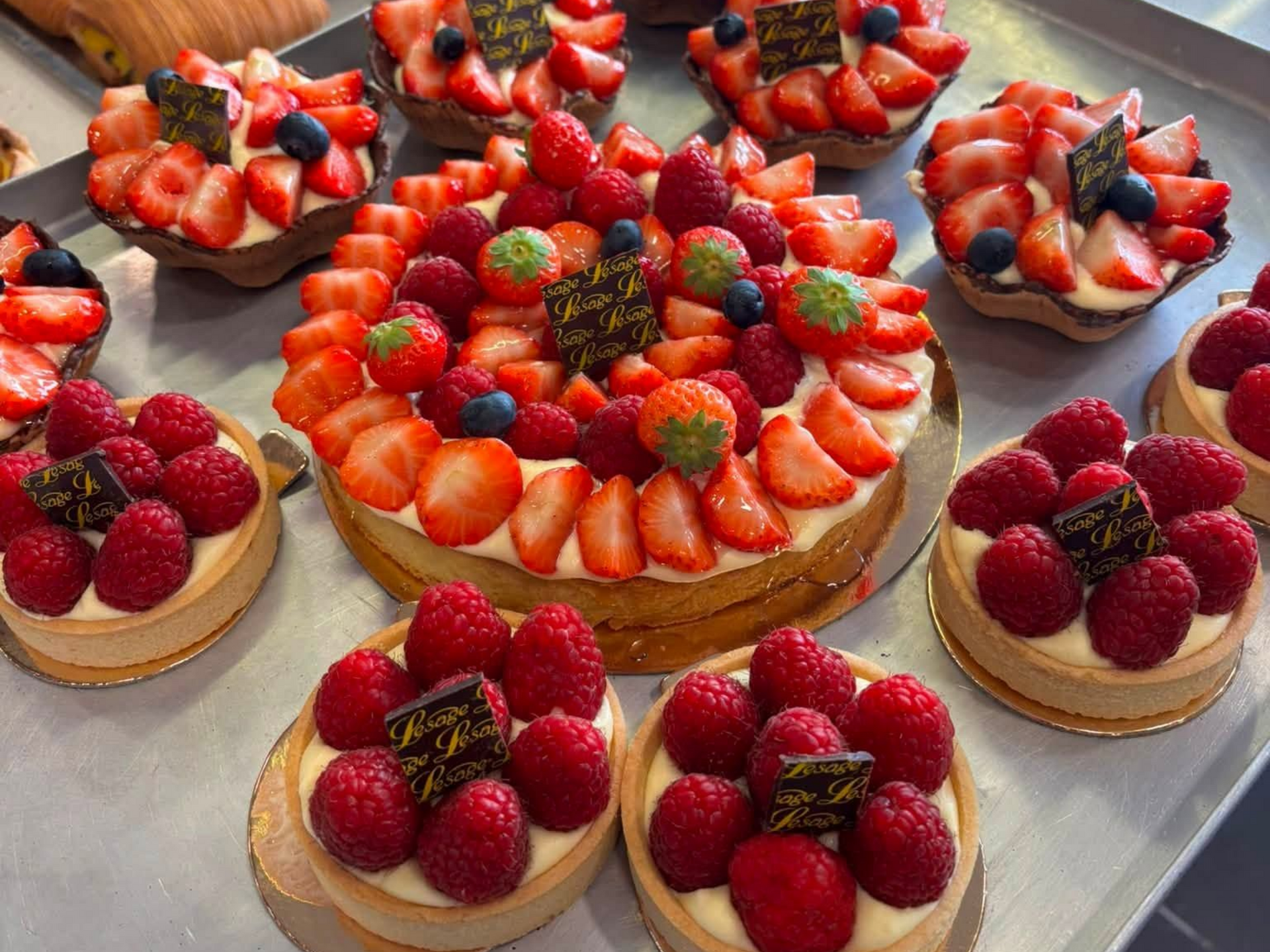 Tarte aux fruits rouges, entourée de tartelettes aux framboises.