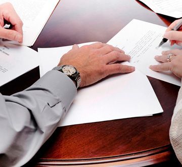 Un hombre que lleva un reloj está escribiendo en un trozo de papel.