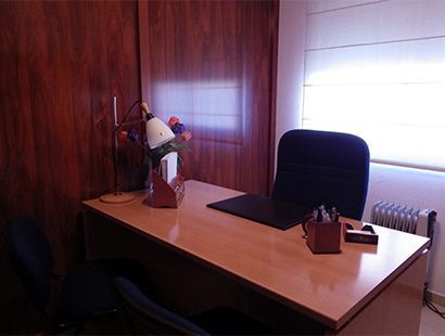 Una pequeña oficina con un escritorio, una silla y una ventana.