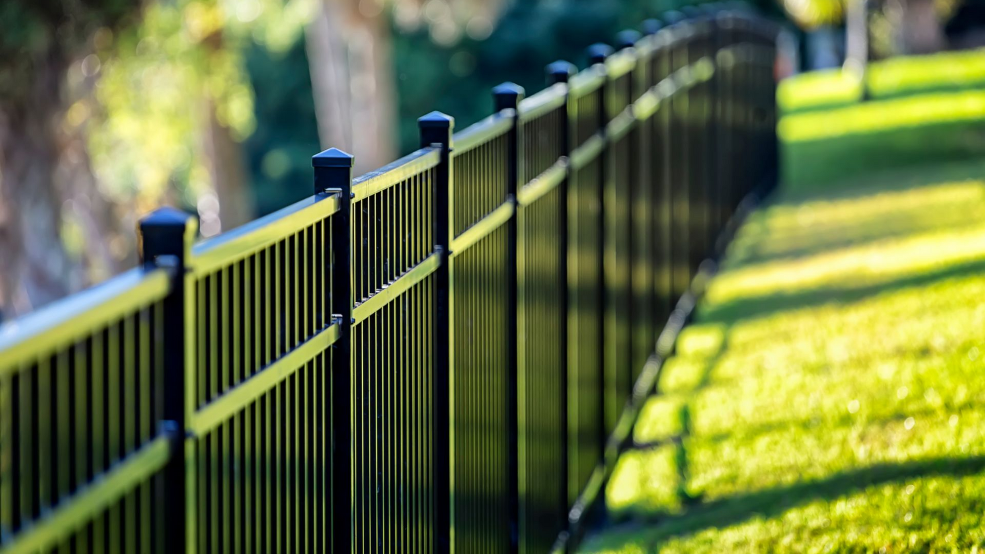 Clôture en métal noir le long d'une pente herbeuse.