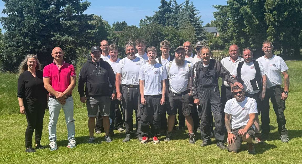 Eine Gruppe von Menschen posiert auf einer Wiese für ein Foto.