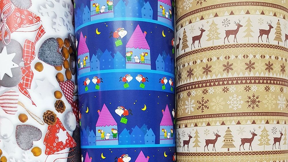 Drei Rollen Weihnachtsgeschenkpapier mit verschiedenen Motiven darauf