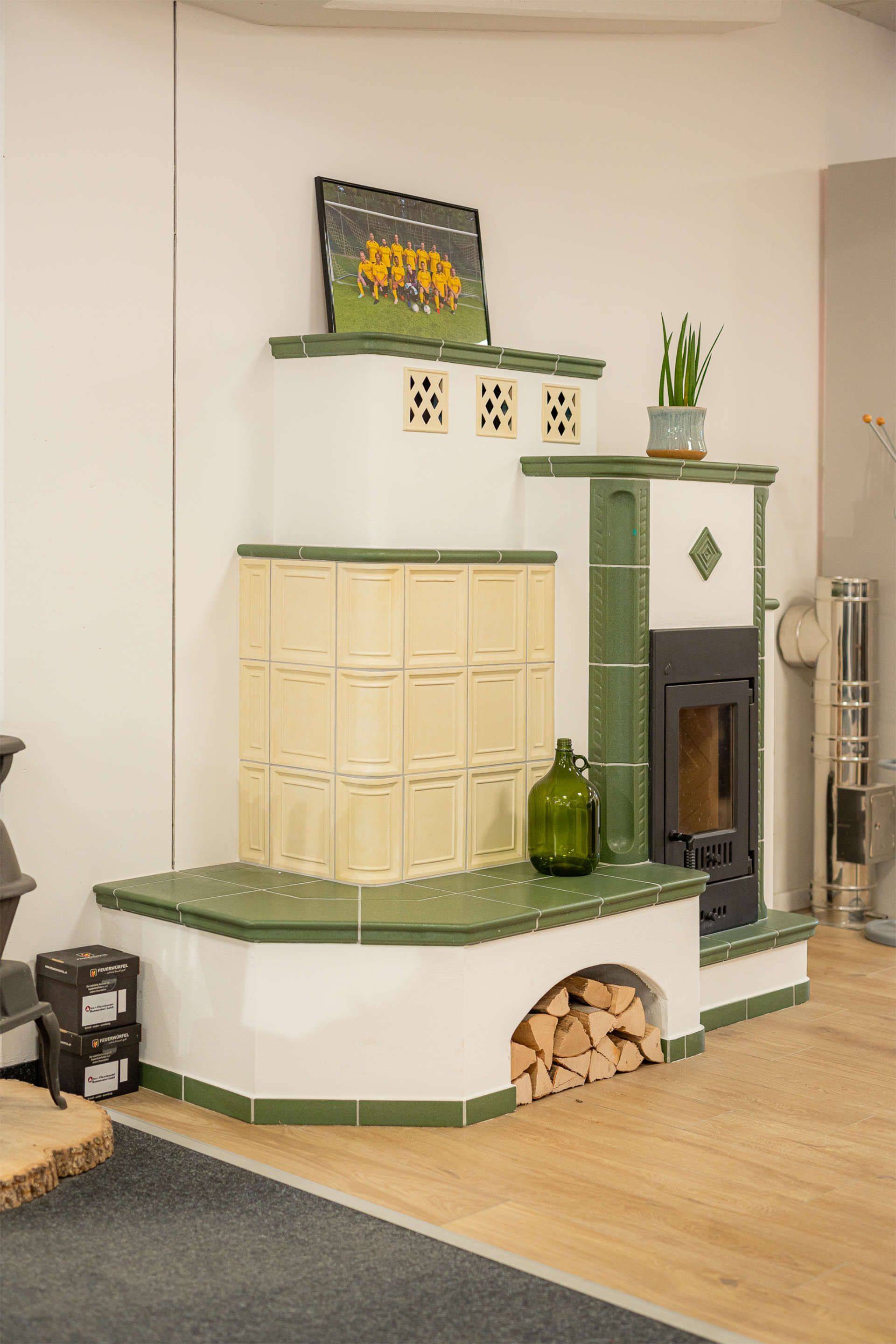 Kachelofen mit beigen und grünen Fliesen im Verkaufsraum von Ofen + Fliesenhandel Mammendorf GmbH