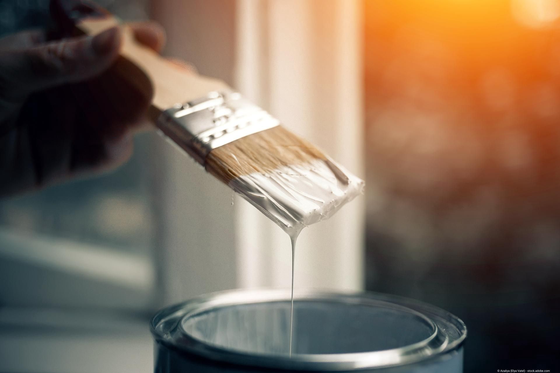 Pinsel mit weißer Farbe über Farbeimer für präzise Malerarbeiten im Innenbereich