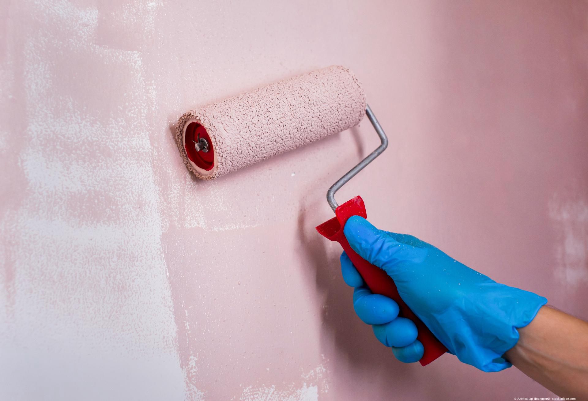 Farbrolle streicht rosa Wand gleichmäßig für saubere und professionelle Wandgestaltung