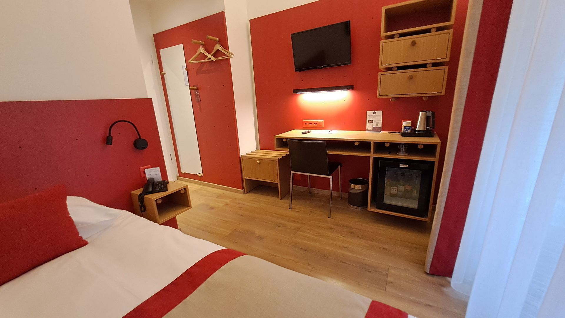 Une chambre d'hôtel avec un lit, un bureau et une télévision.