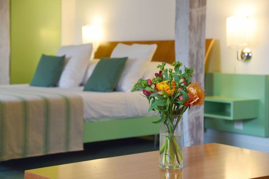 Une chambre d'hôtel avec un lit et un vase de fleurs sur une table.