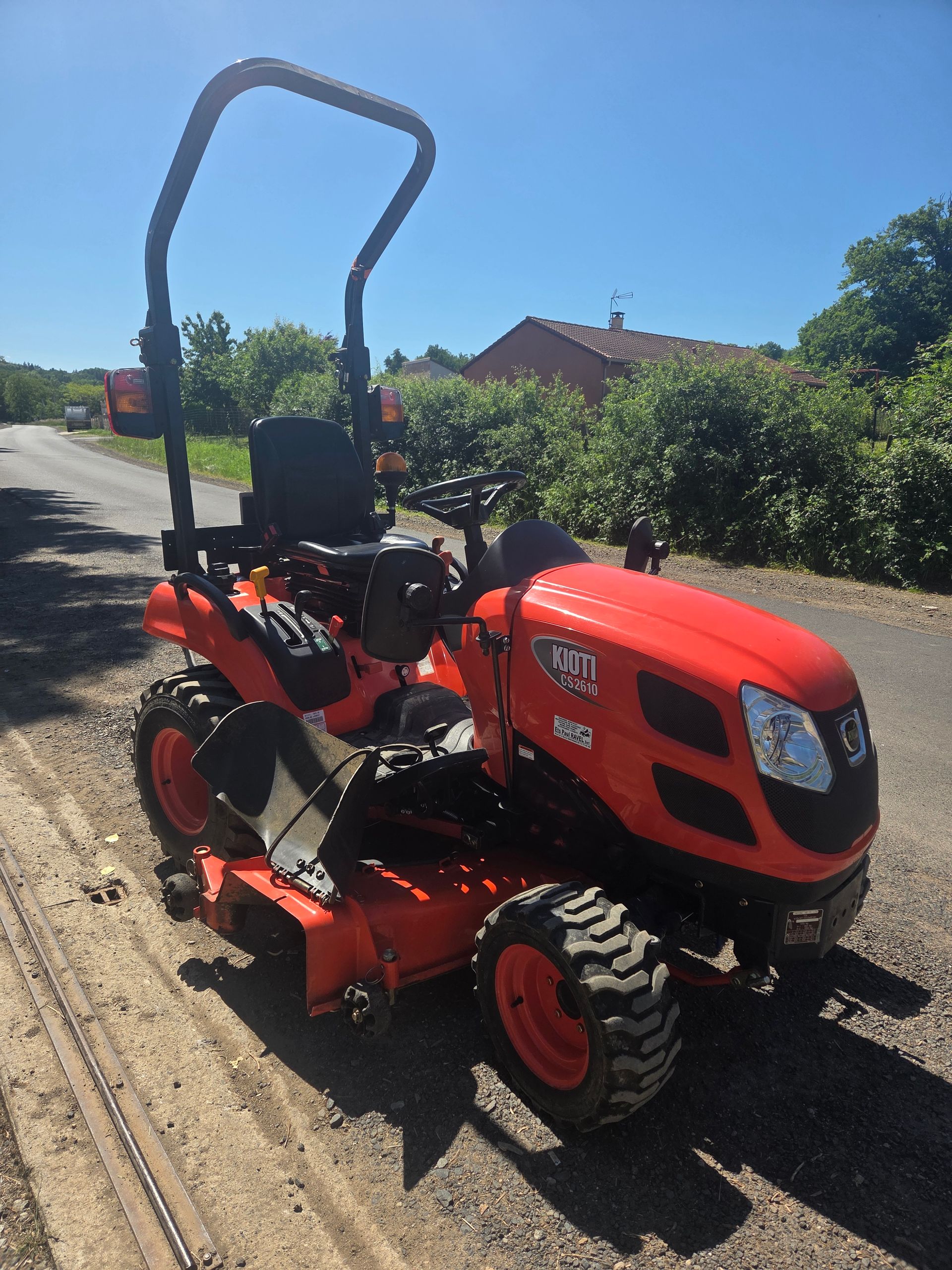 Tracteur compact rouge stationné dans un garage ou un atelier.