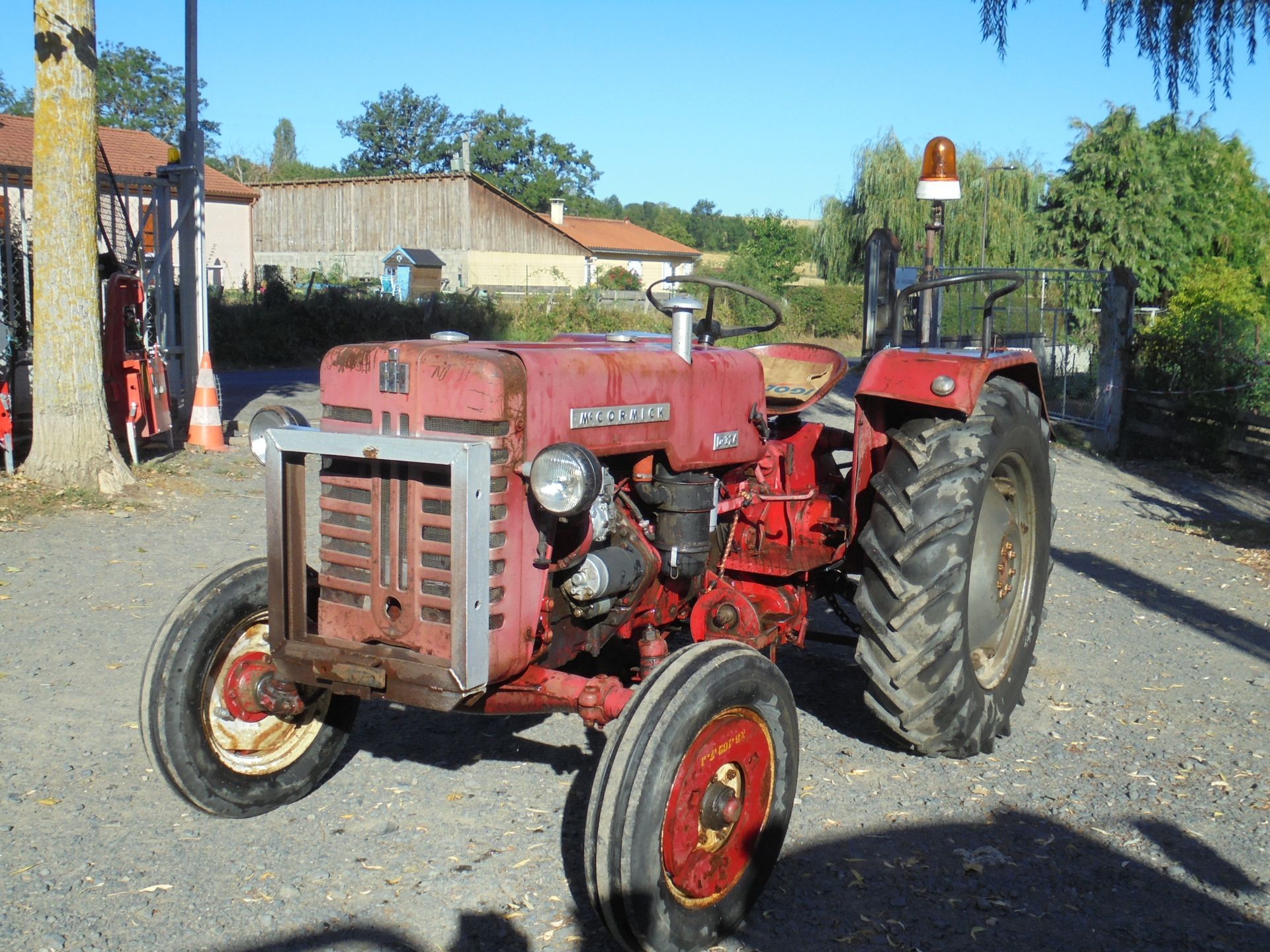 Tracteur rouge vintage garé sur du gravier à l'extérieur