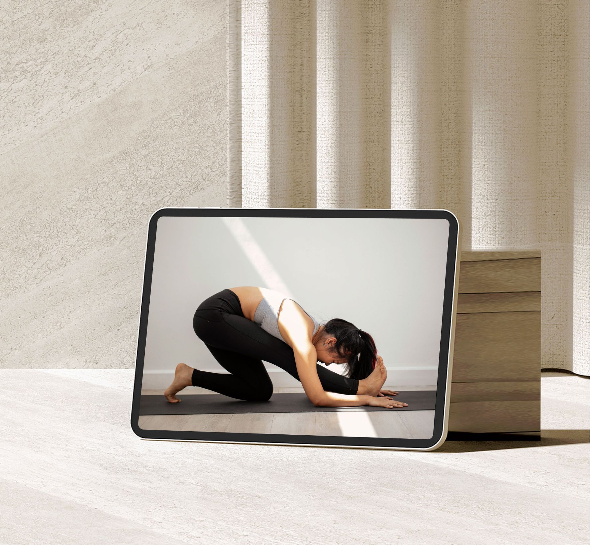 Une femme s'étire sur l'écran d'une tablette à côté de blocs de yoga empilés dans un studio lumineux