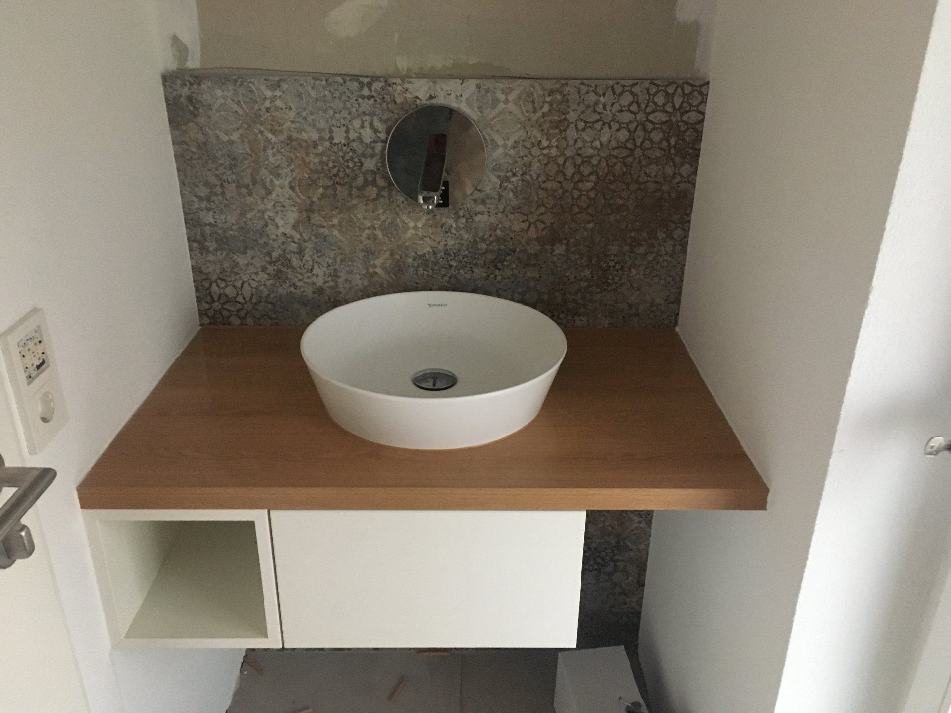 Ein Badezimmer mit Waschbecken und Holzablage.