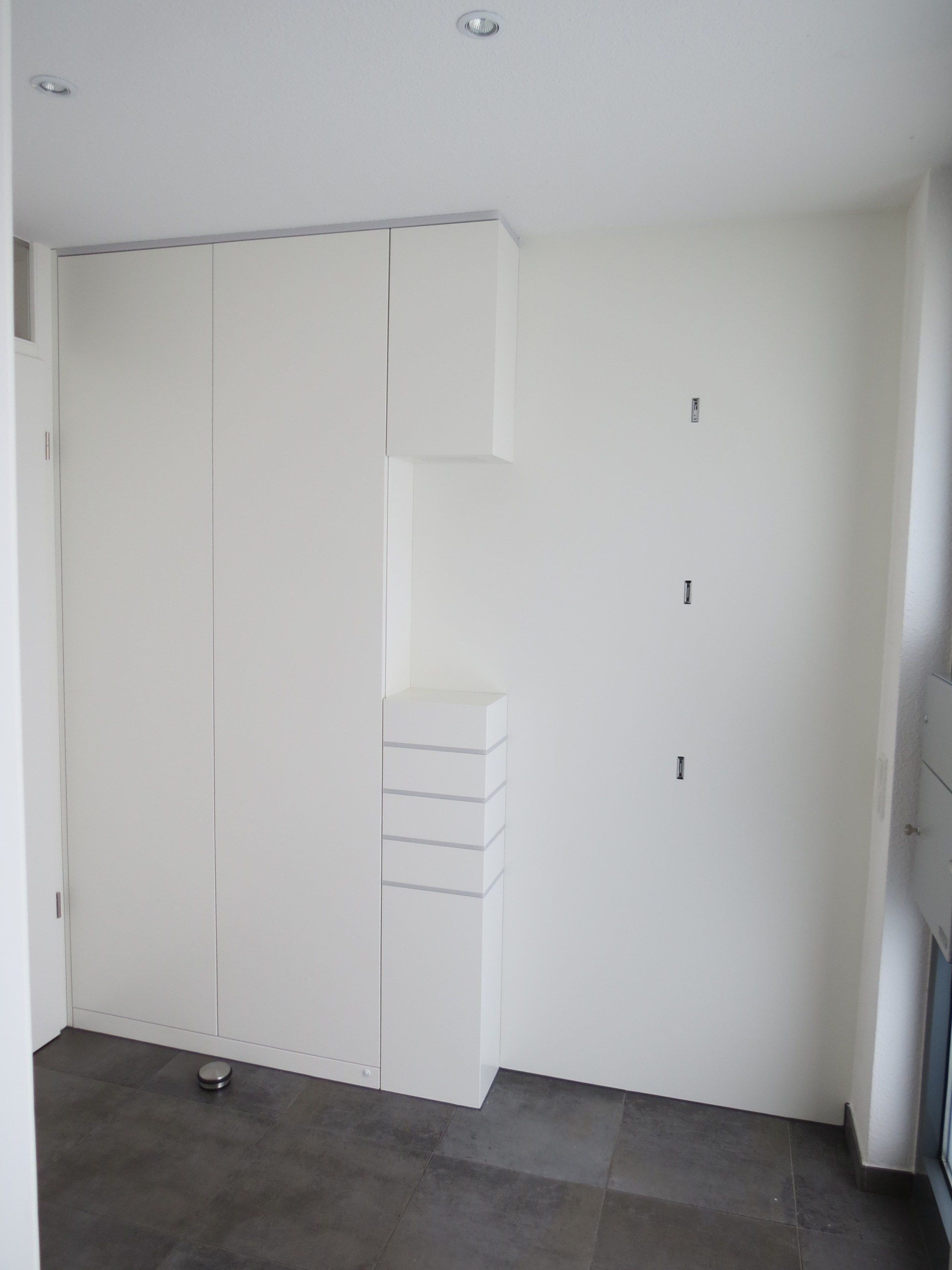 Ein Zimmer mit vielen weißen Schränken und Schubladen.