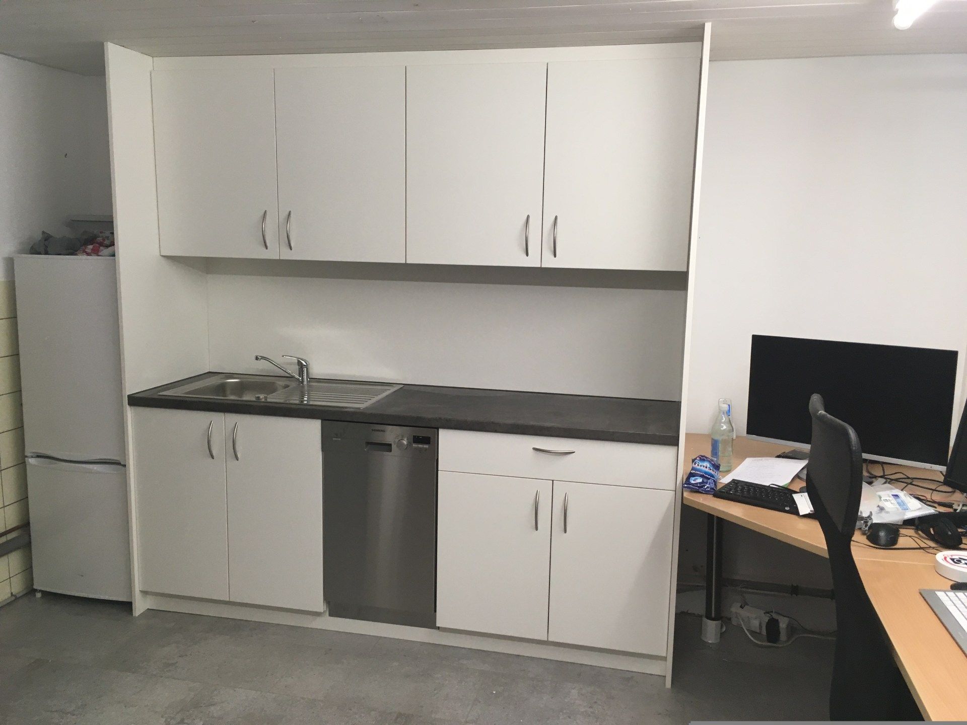 Eine Küche mit weißen Schränken und einem Geschirrspüler aus Edelstahl.