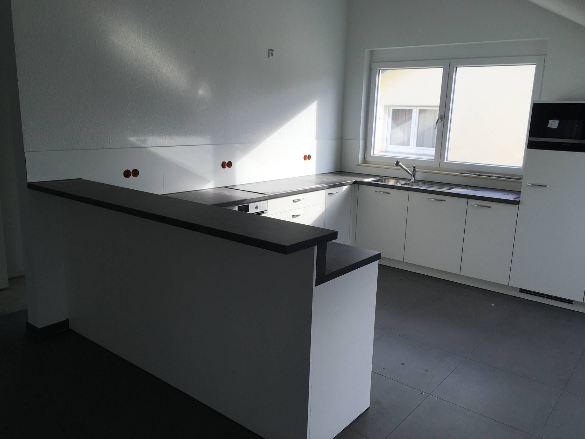 Eine leere Küche mit weißen Schränken und einem Fenster