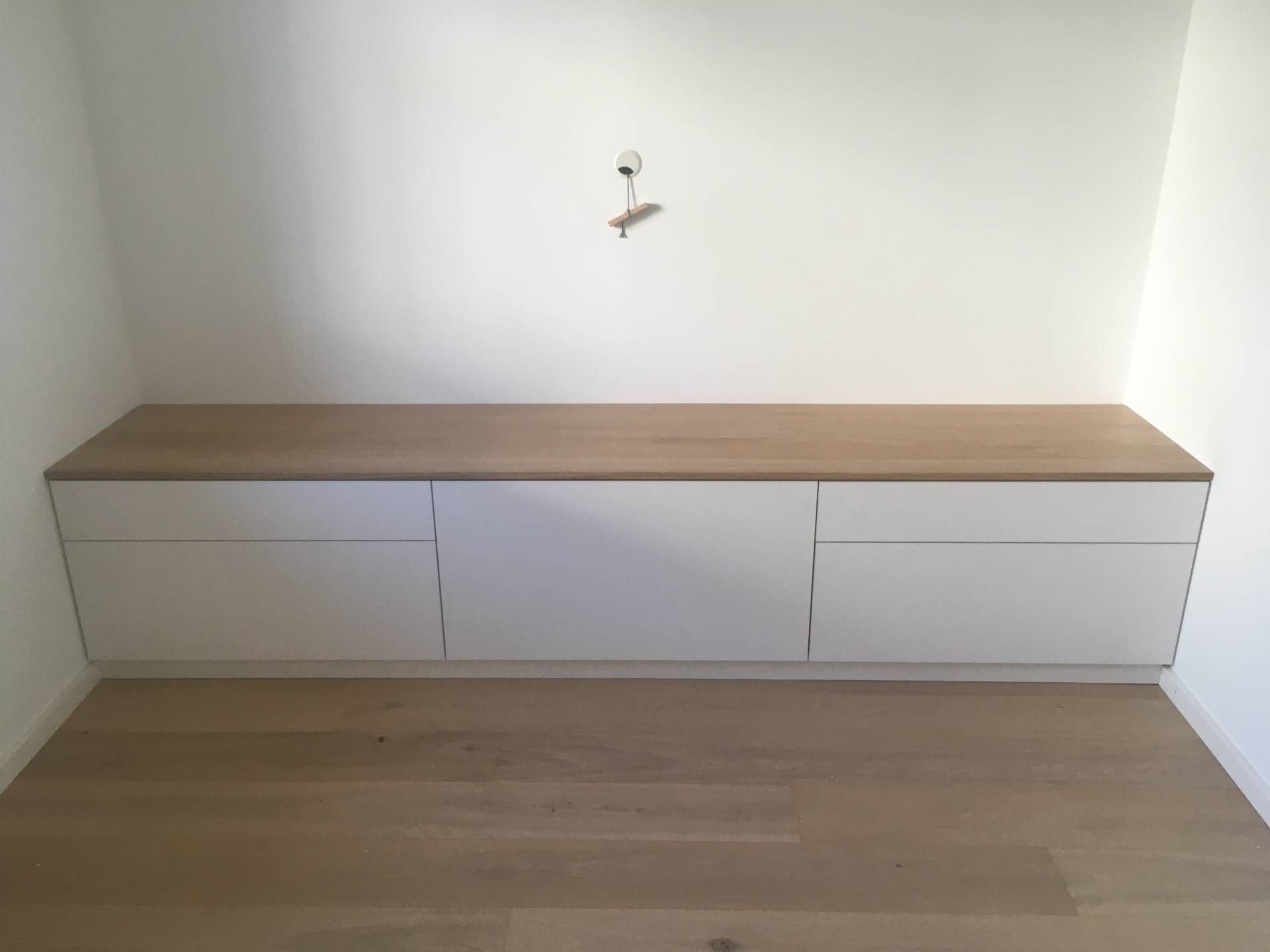 Ein weißer Schrank mit einer Holzplatte in einem Zimmer.