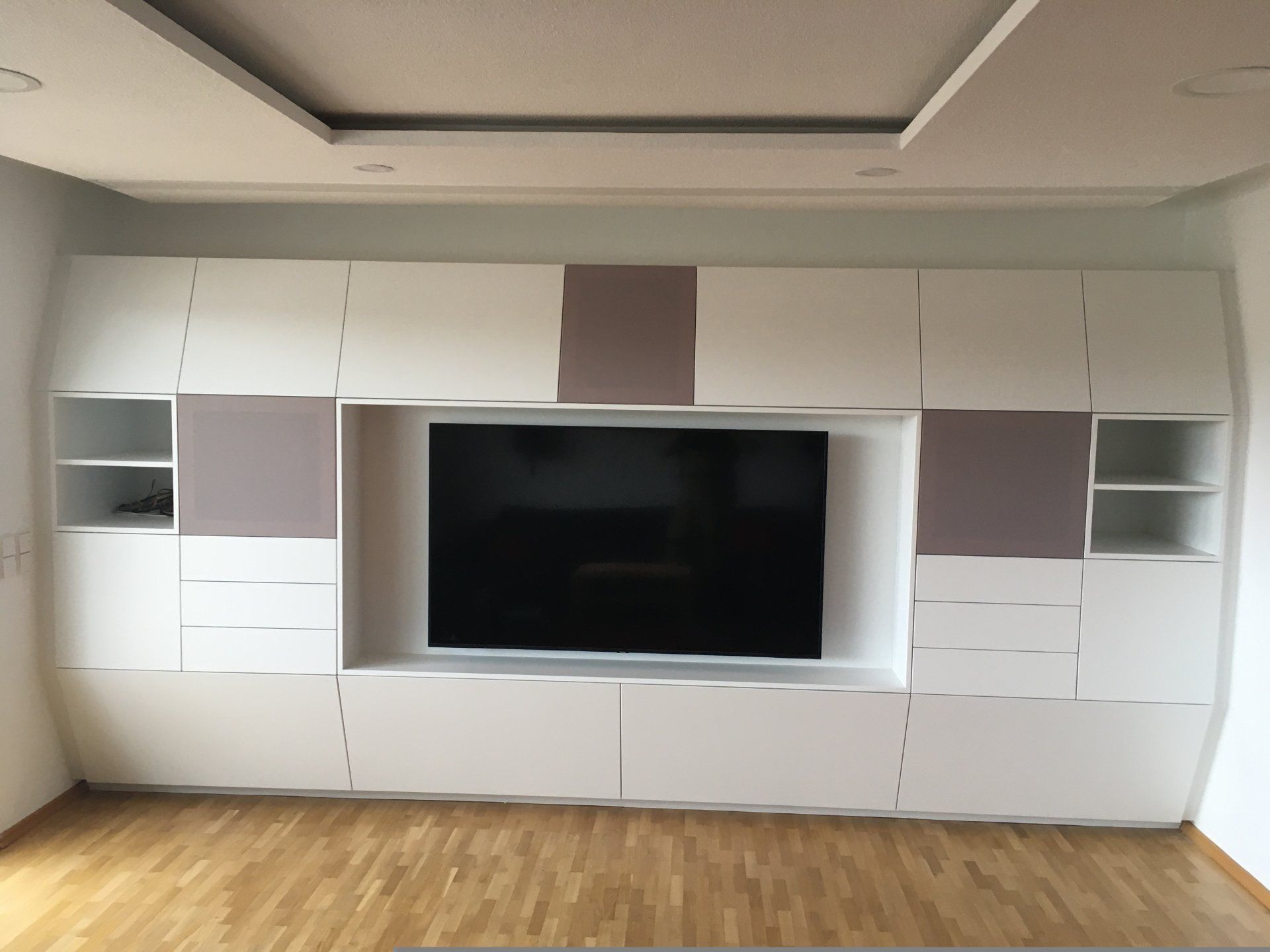 Ein Wohnzimmer mit weißen Schränken und einem Flachbildfernseher.