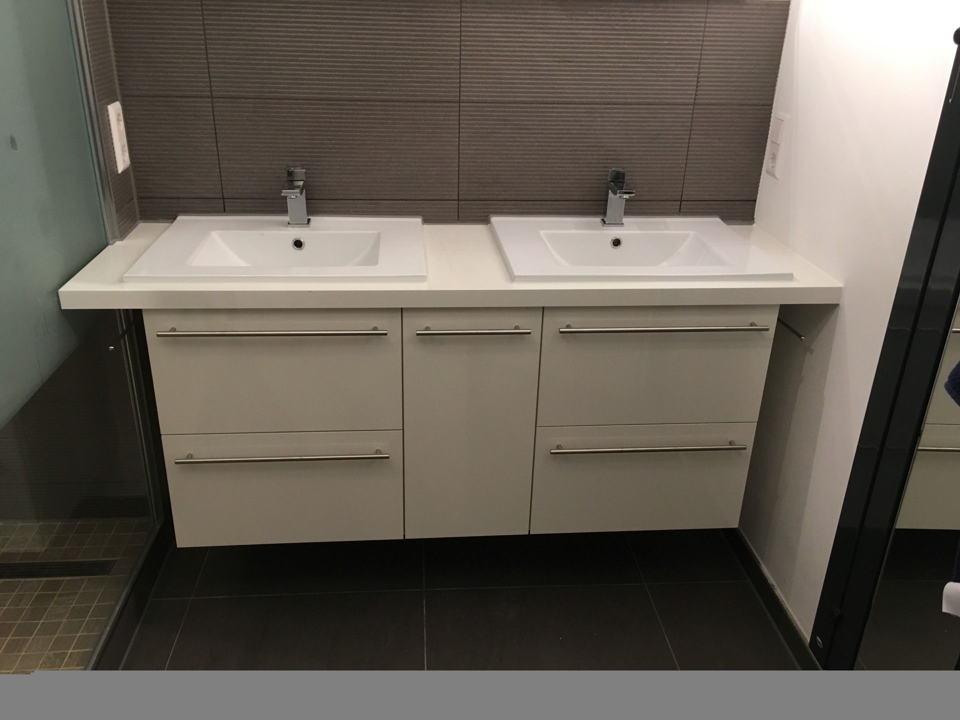 Ein Badezimmerschrank mit zwei Waschbecken und Schubladen.