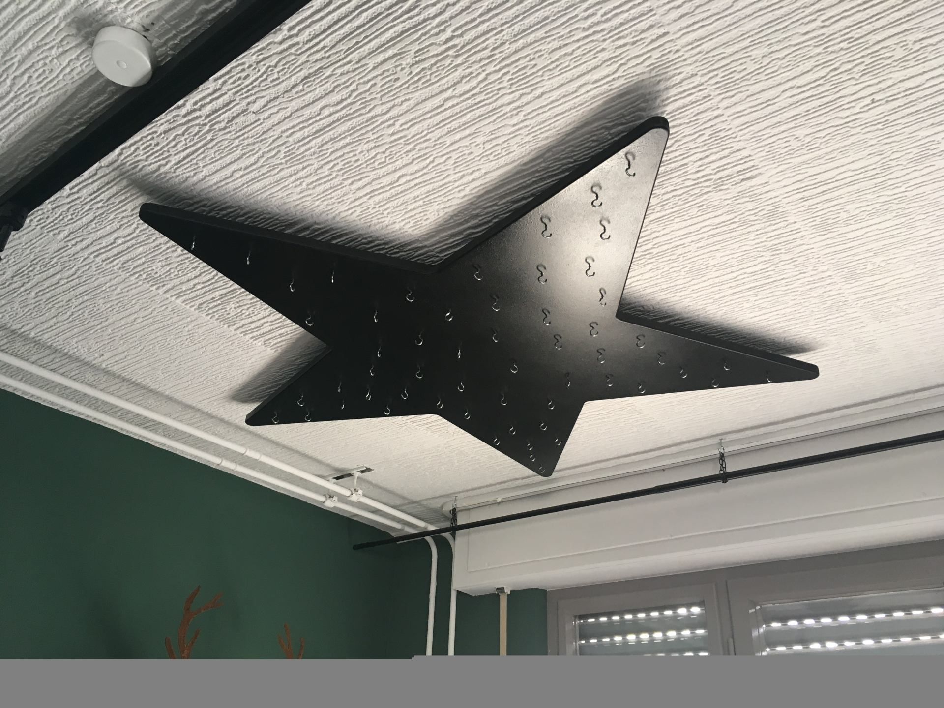 Eine schwarze Sternenlampe hängt von der Decke eines Zimmers.