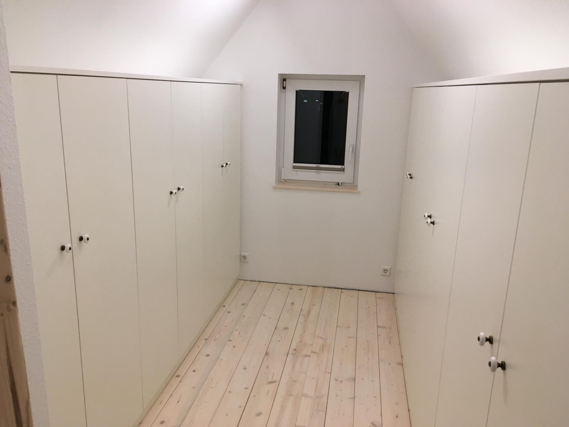 Ein Raum mit vielen weißen Schränken und einem Fenster.