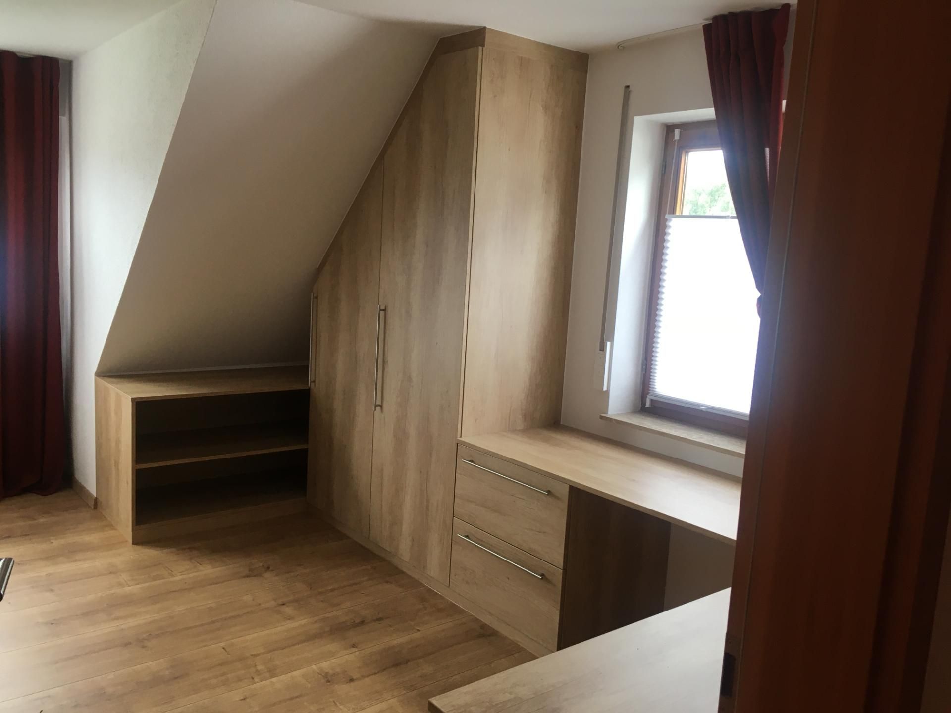 Ein Zimmer mit Fenster und Holzschränken.