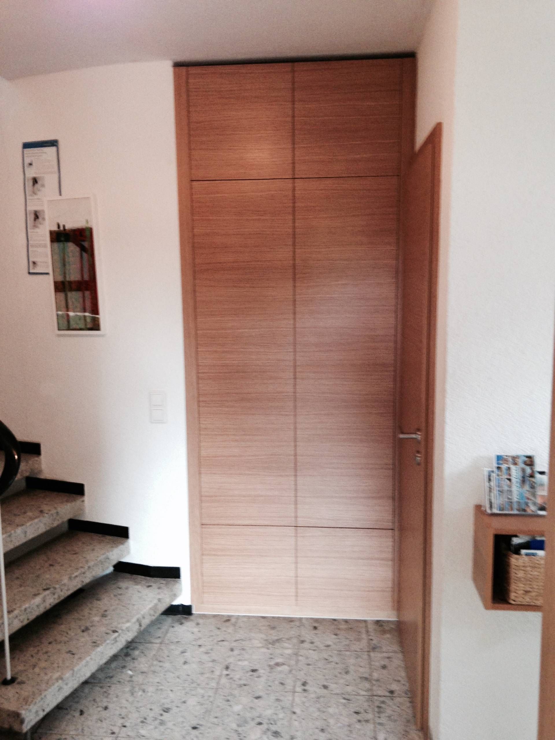 Ein Flur mit Treppe und einer Holztür.