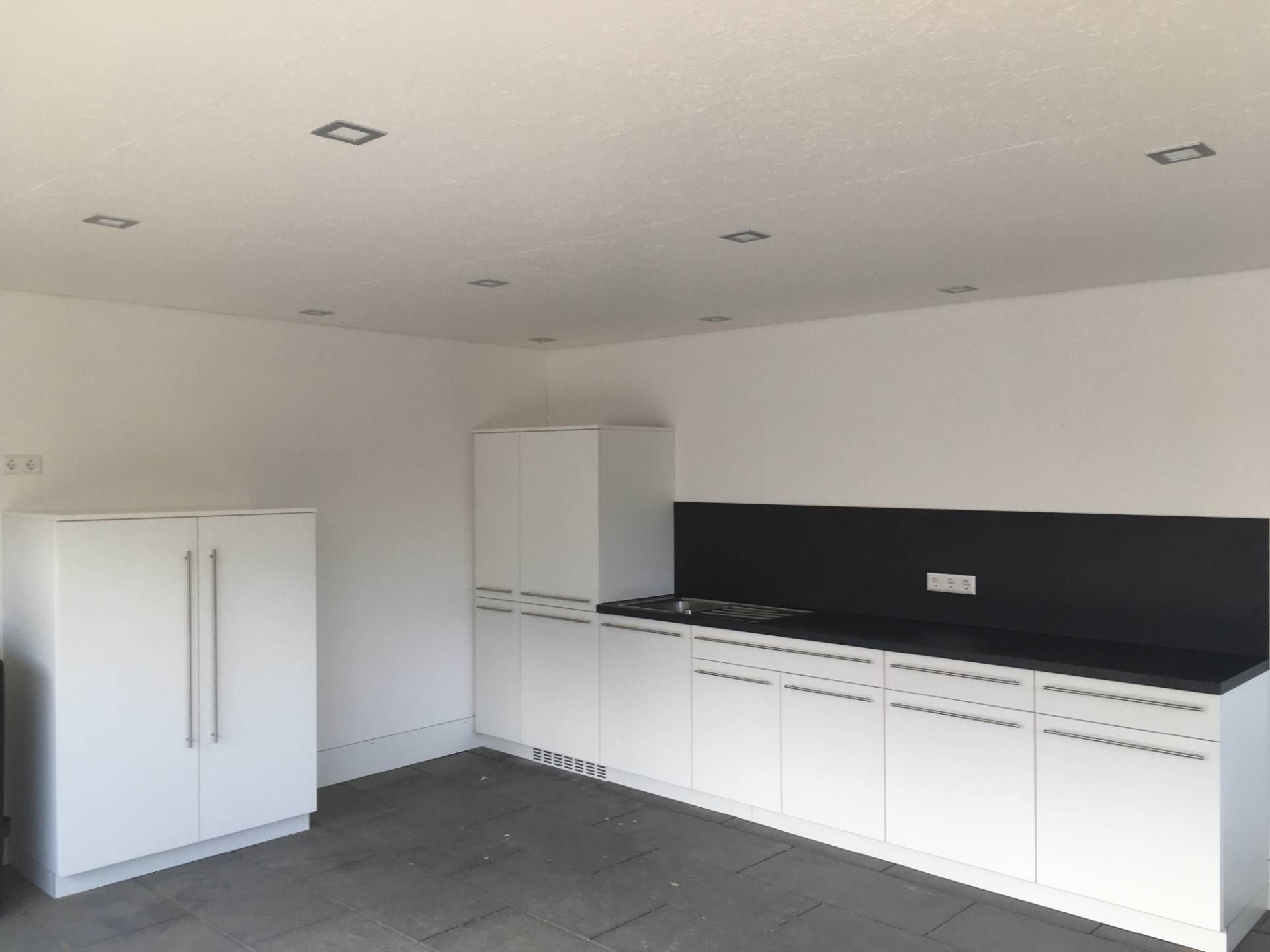 Eine Küche mit weißen Schränken und schwarzen Arbeitsplatten.