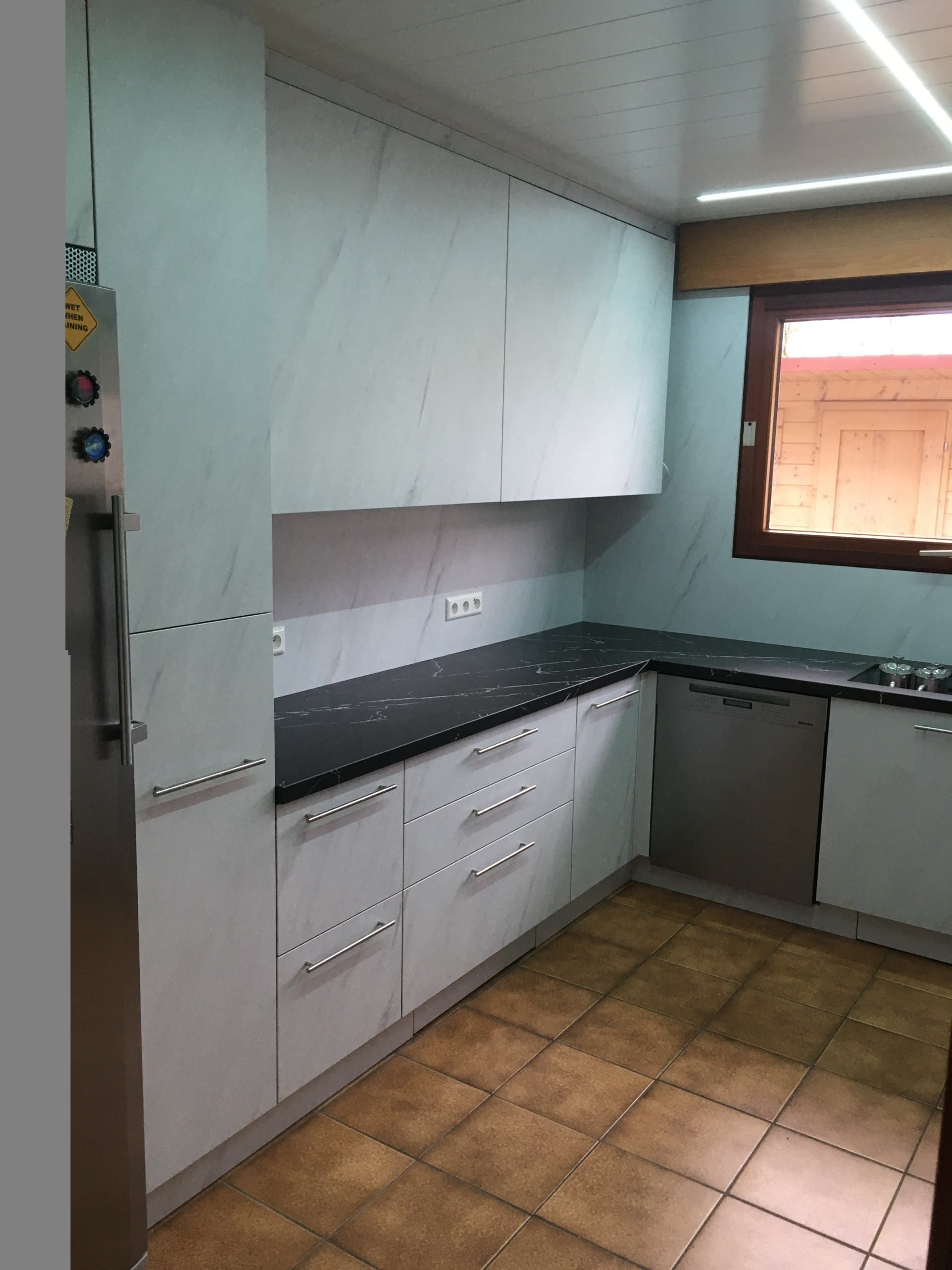 Eine Küche mit weißen Schränken und schwarzen Arbeitsplatten.