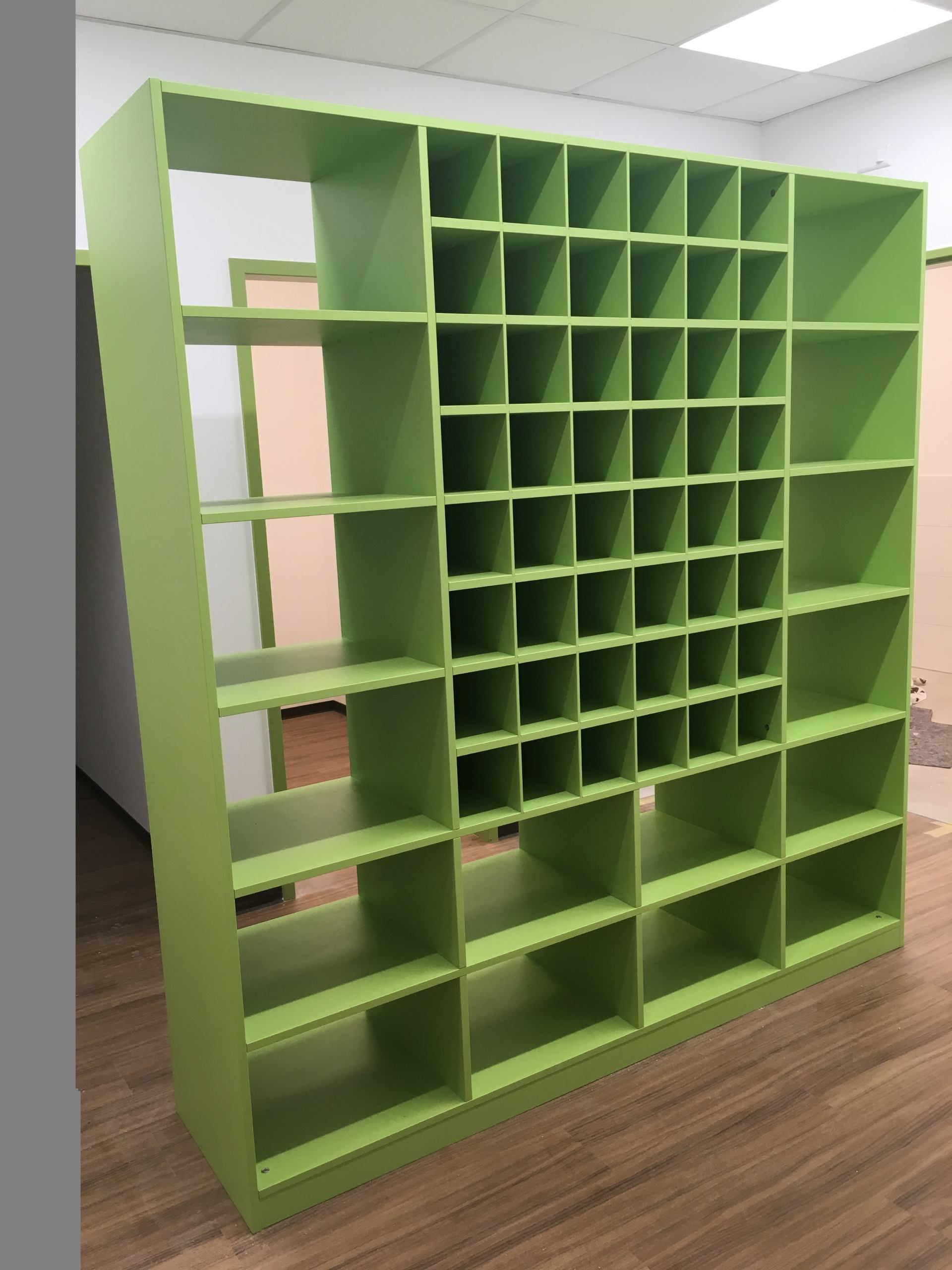 Ein grünes Regal mit vielen Regalen in einem Raum.