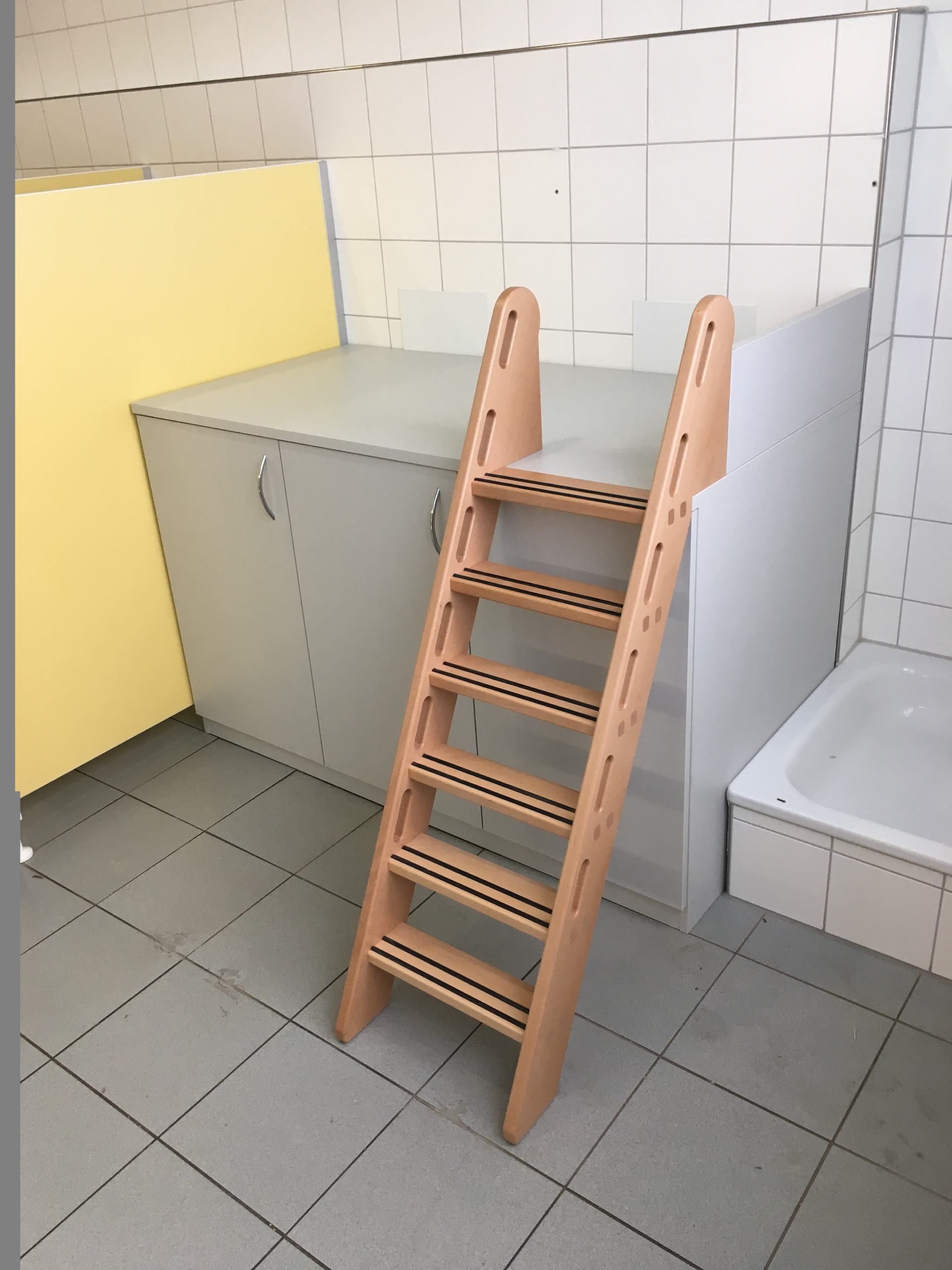 Eine Holzleiter in einem Badezimmer neben einer Badewanne.